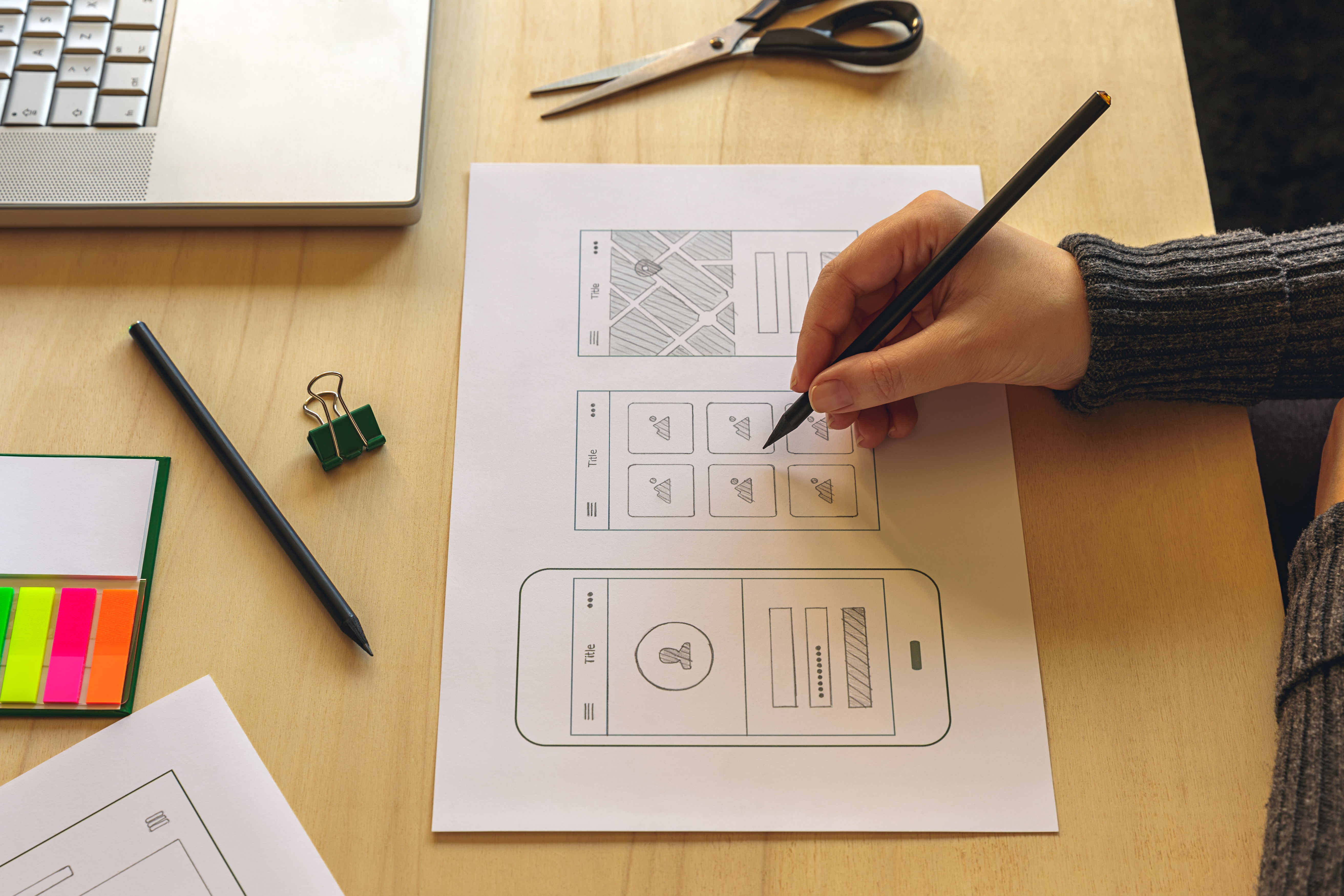 Designer wireframing a mobile App on wooden desk